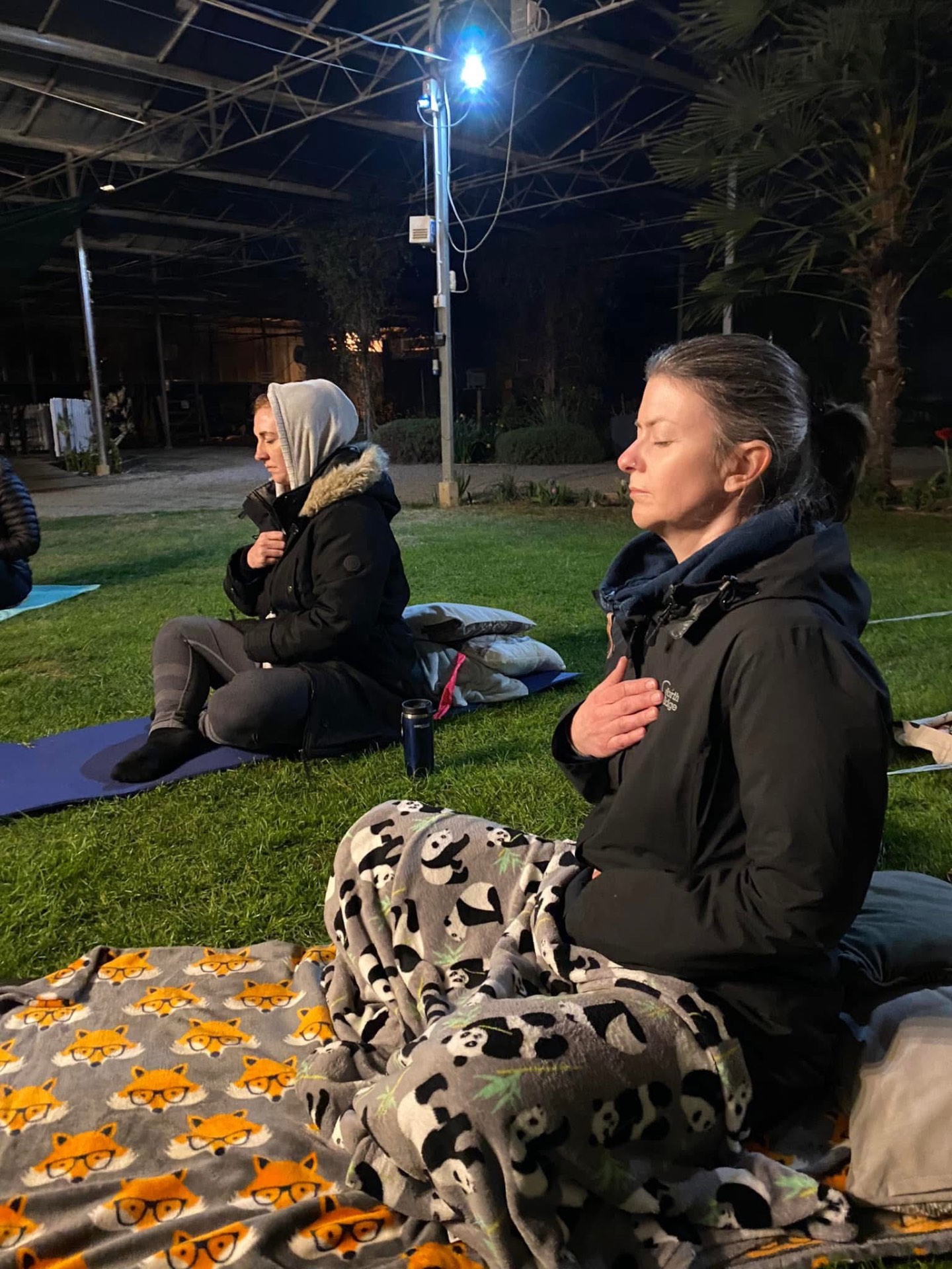 Evening meditation outdoors, wrapped in blankets under warm lights