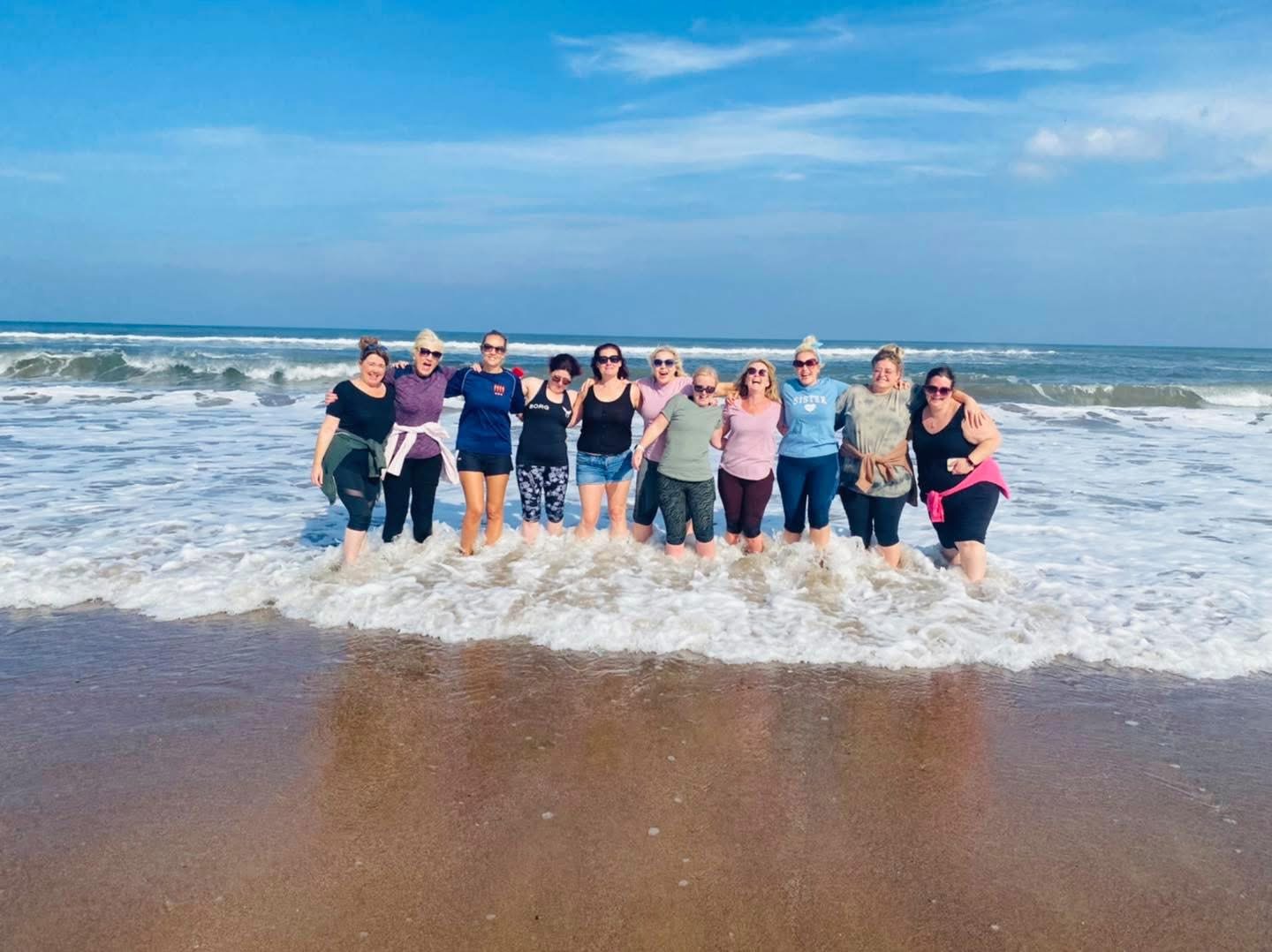 Retreat group arm in arm in the surf on a blue-sky day