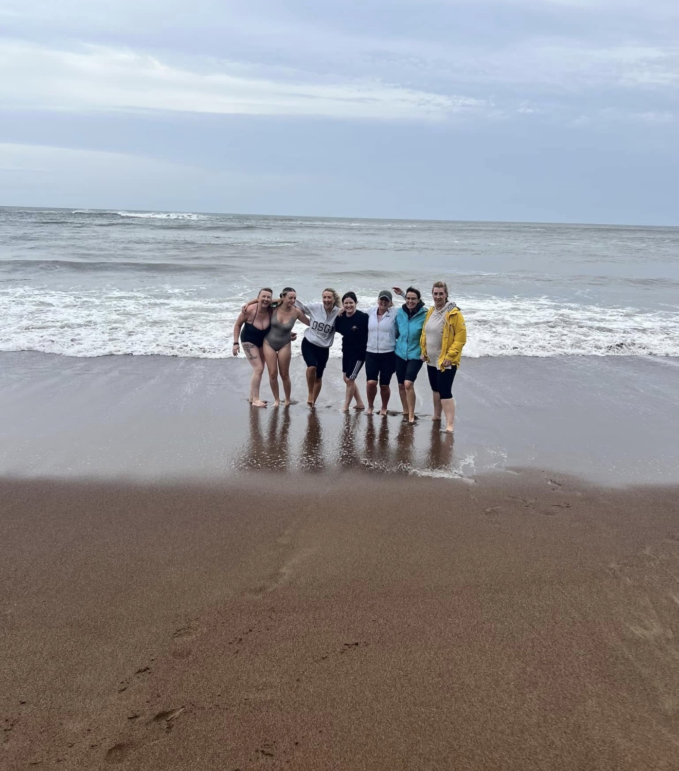 Group standing in the shallows on a moody Yorkshire shoreline