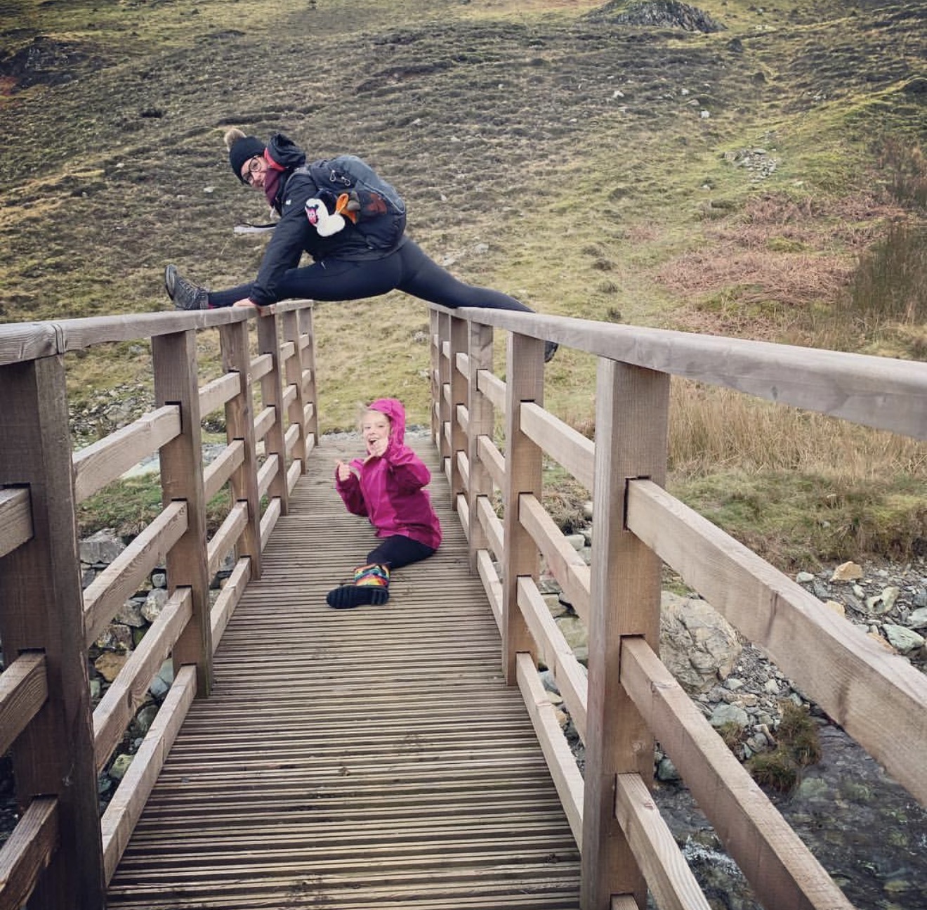 Splits across the handrails of a moorland footbridge, with a laughing child below